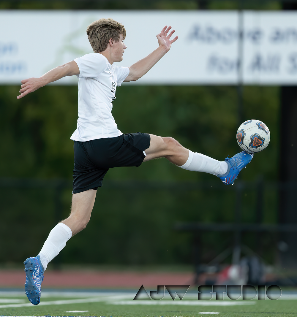 Soccer player executes a high kick to control the ball during a match.