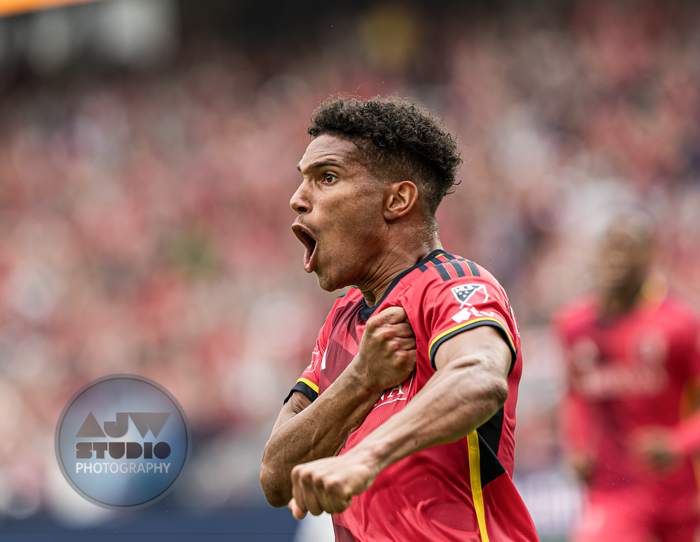 Professional MLS soccer player celebrates passionately in red uniform during a match.