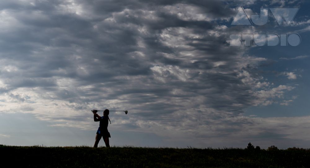Dramatic silhouette of golfer against stormy sky during swing.