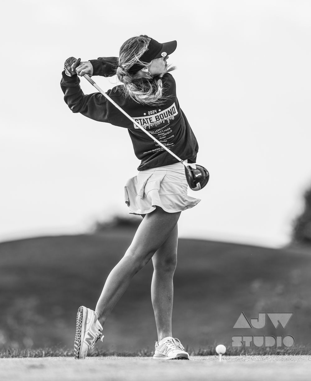 Black and white photo of golf swing follow-through on hillside course.