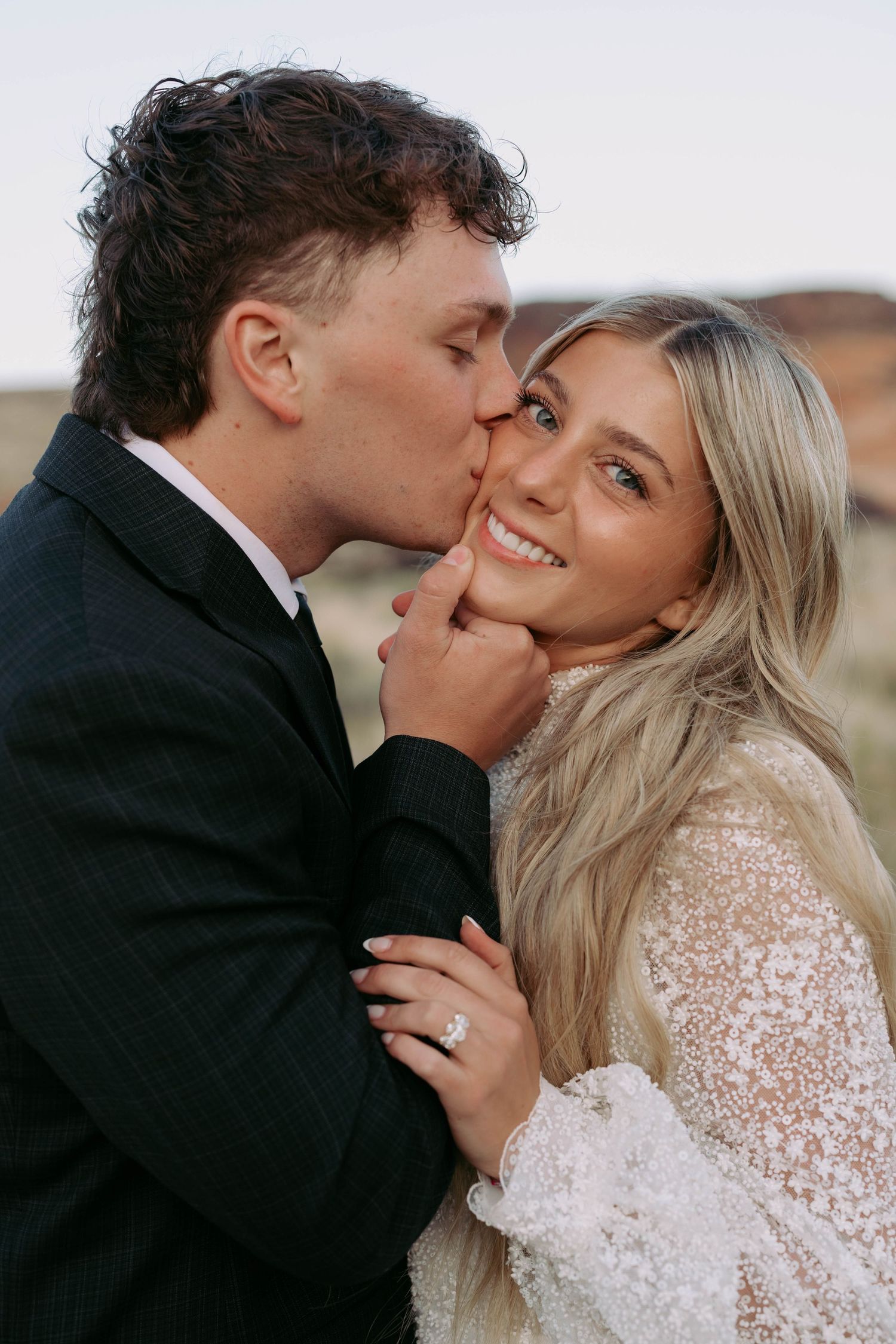 A couple sharing a kiss with a stunning fall mountain landscape of Utah in the background.