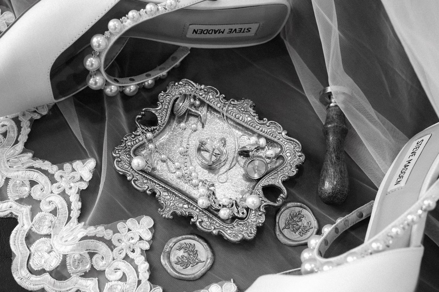 A black and white photo of vintage ornate framed decorative objects with pearls and ribbons.