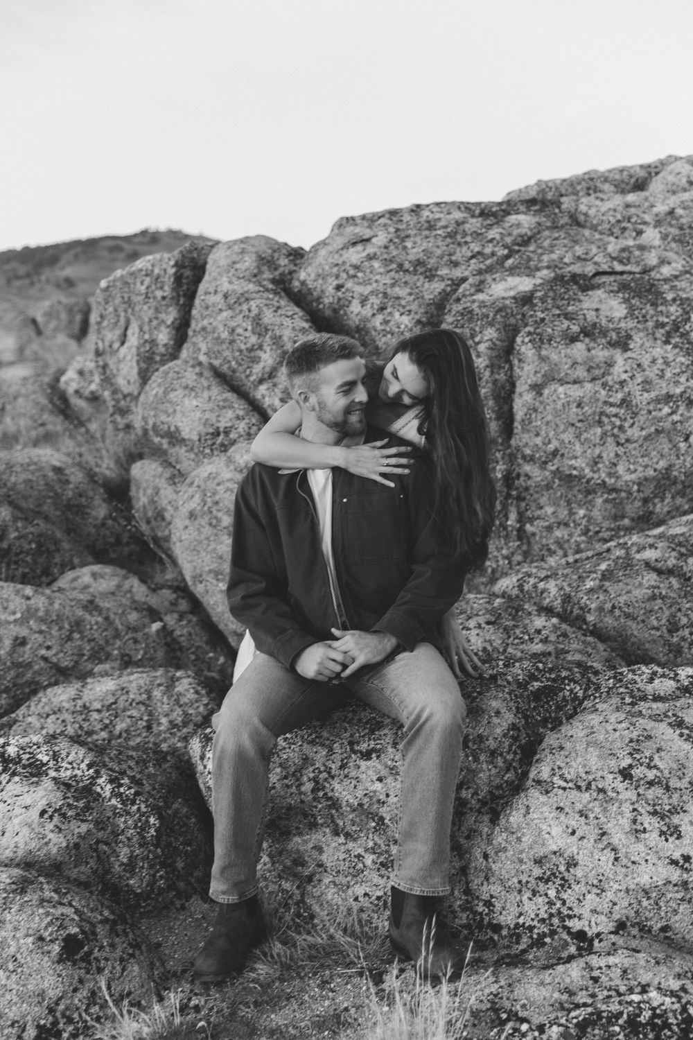 Black and white series showing a couple sitting intimately on rocky terrain.