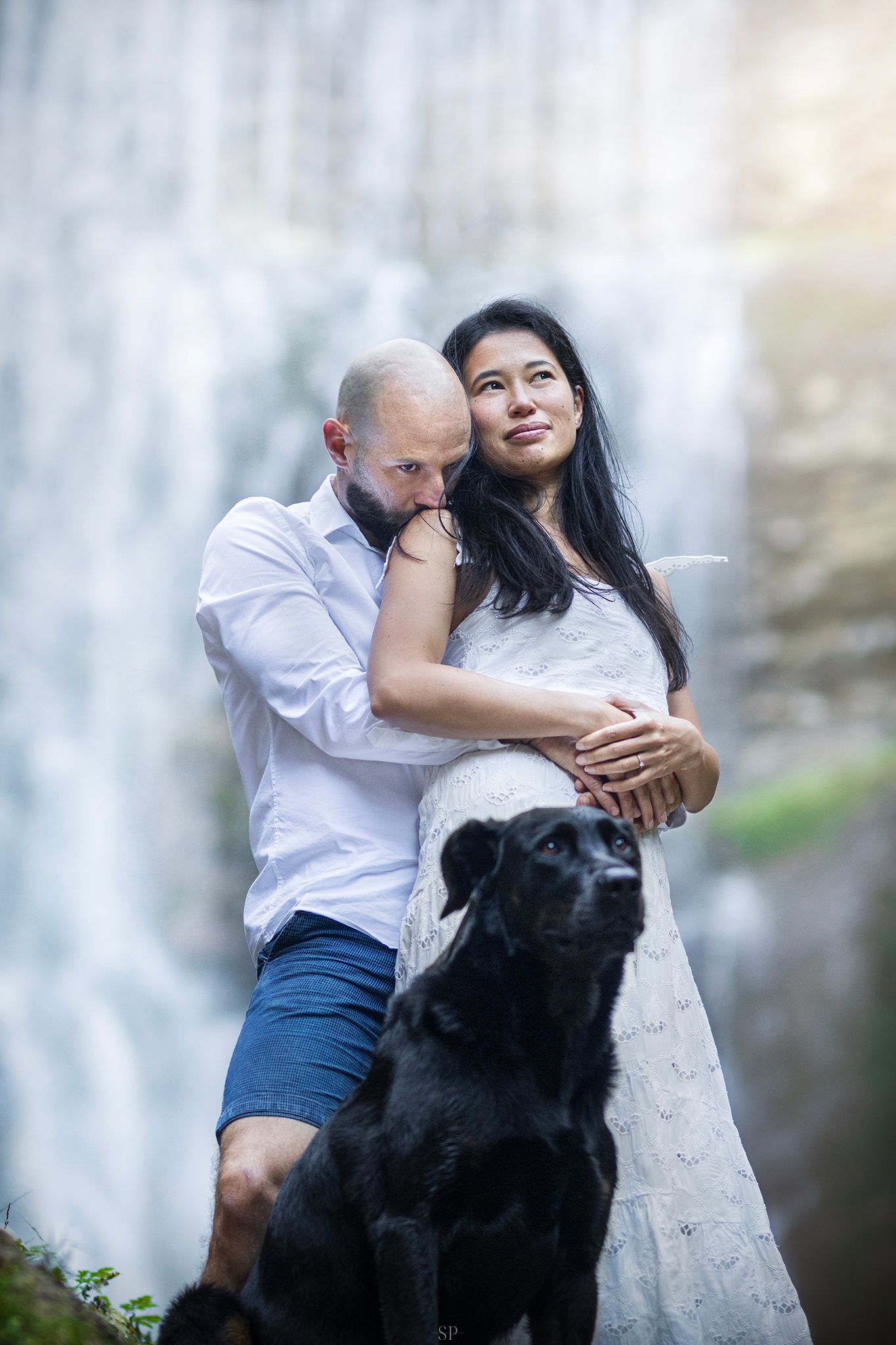 Couple et leur beauceron devant une cascade