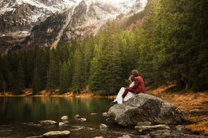 Couple de mariés devant un lac avec une forêt et une montagne en fond