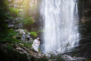 Couple et leur beauceron devant une cascade
