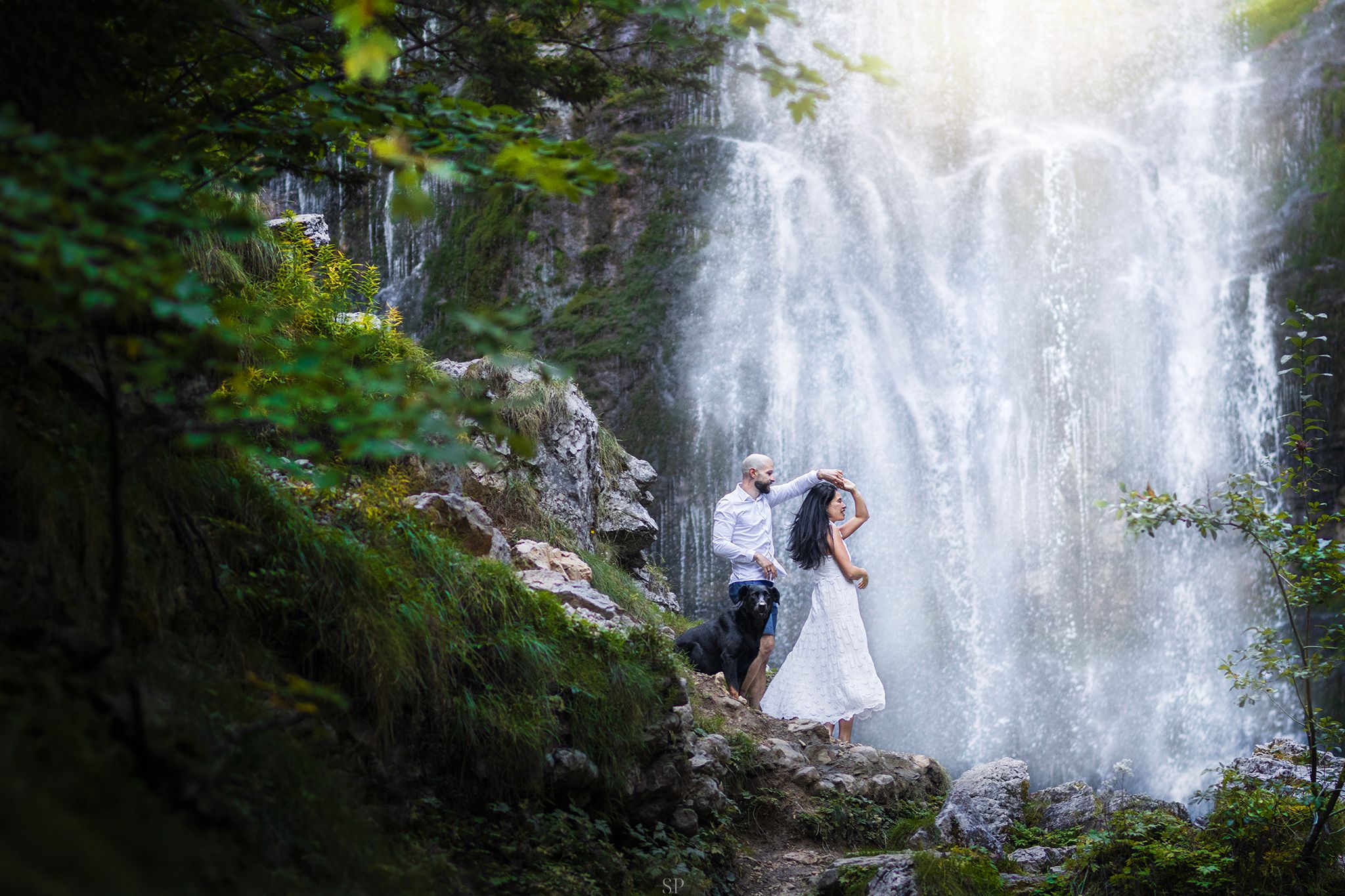 Couple et leur beauceron devant une cascade