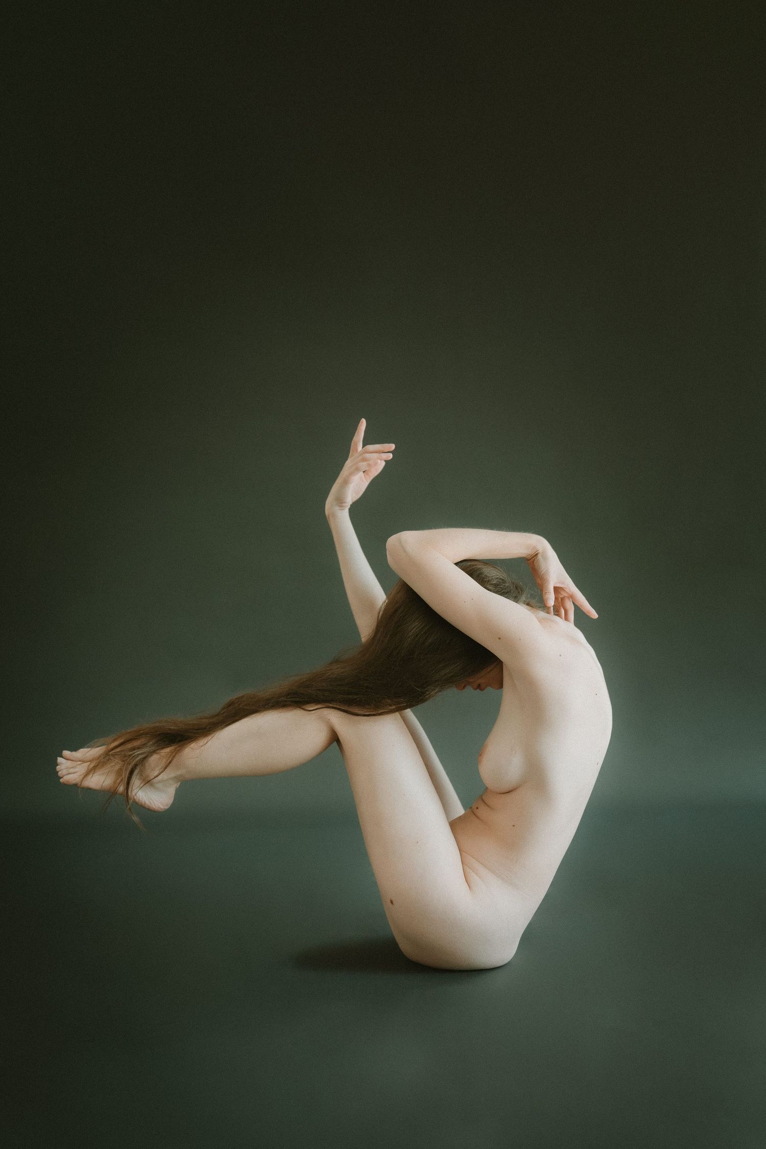 Dynamic nude figure study displaying graceful dance-like pose against green backdrop.