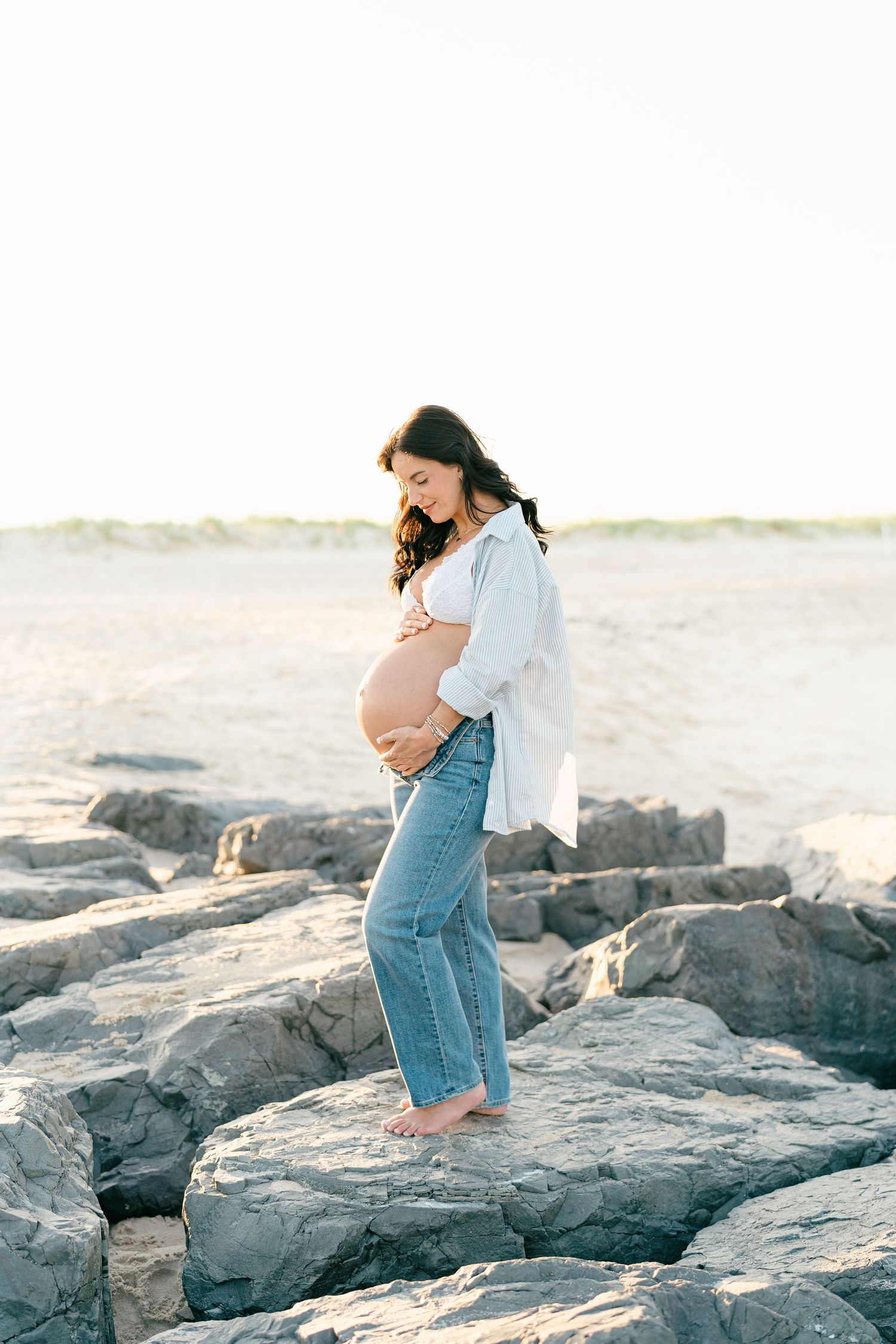 A portrait of a woman that is thirty five weeks pregnant on a jetty at the beach in sea girt nj.