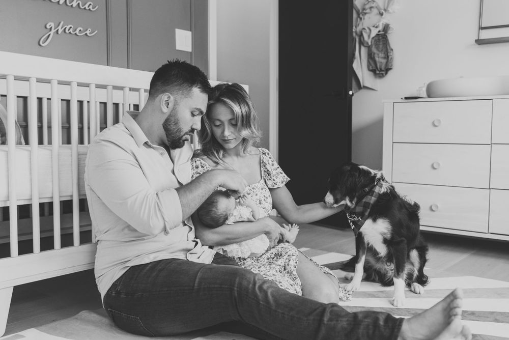 A black and white image of a family in the nursery looking at their newborn baby.