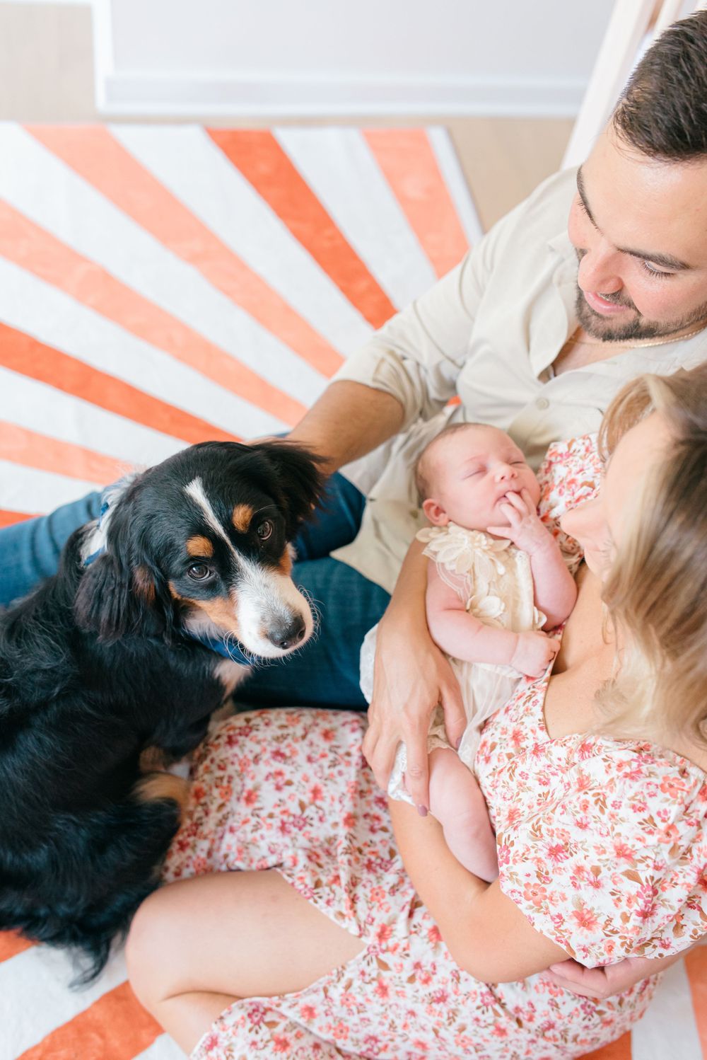 An above image of a family of three with their family dog sitting on the floor of a nursery.