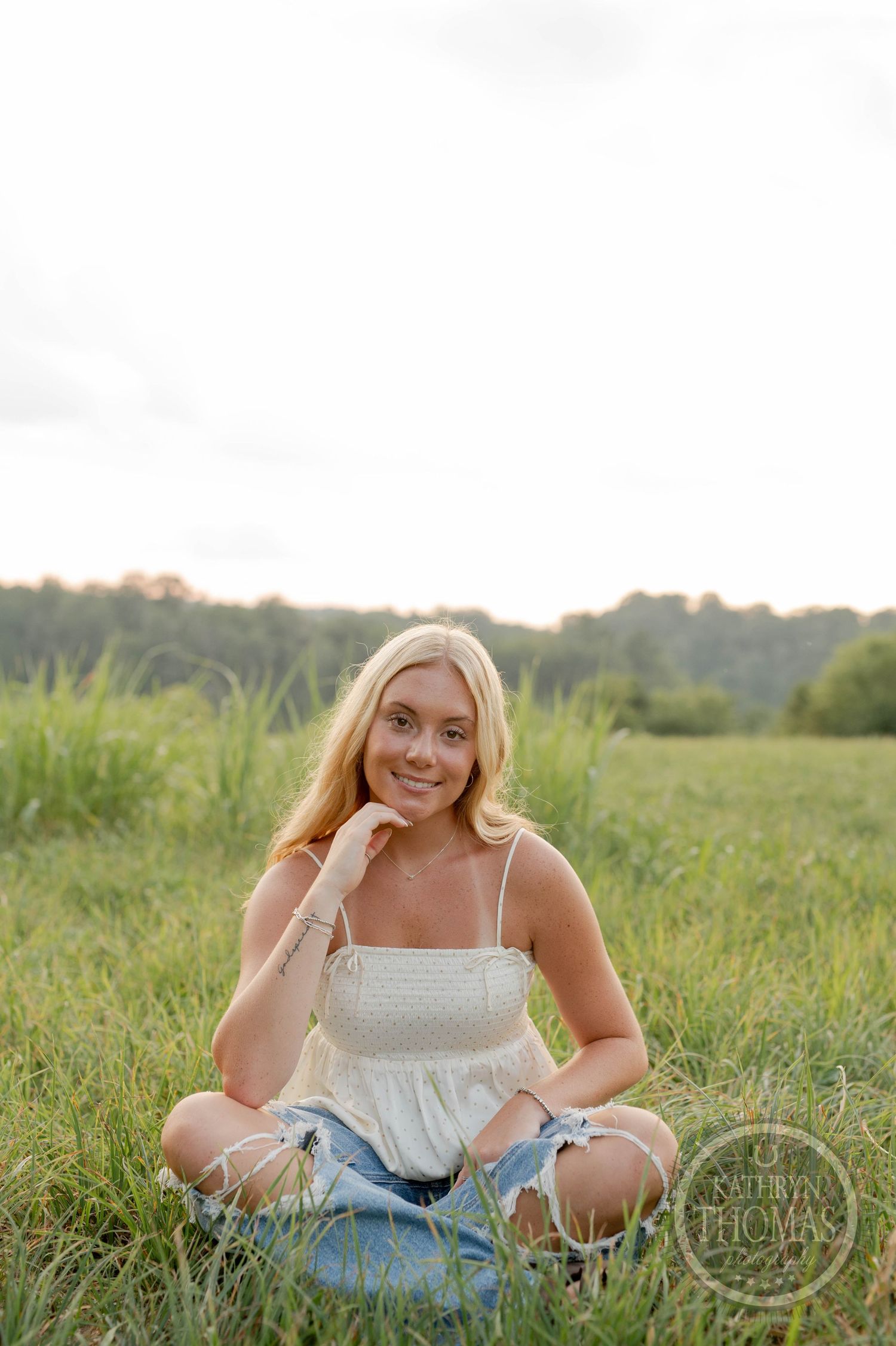 Candid outdoor portrait sitting in tall grass during golden hour.