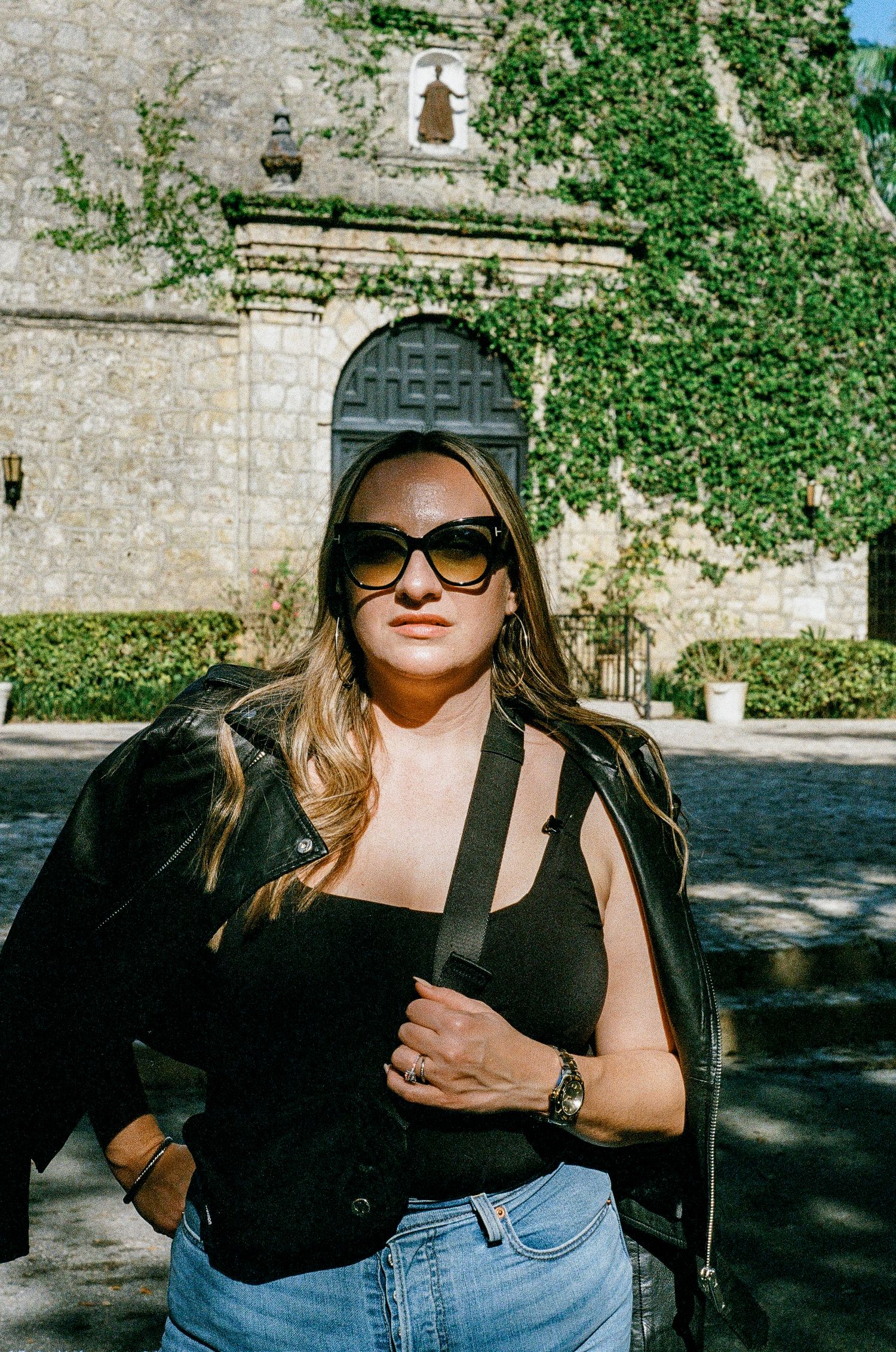A sunny day outside an old stone church with ivy-covered walls and a grand arched entrance.