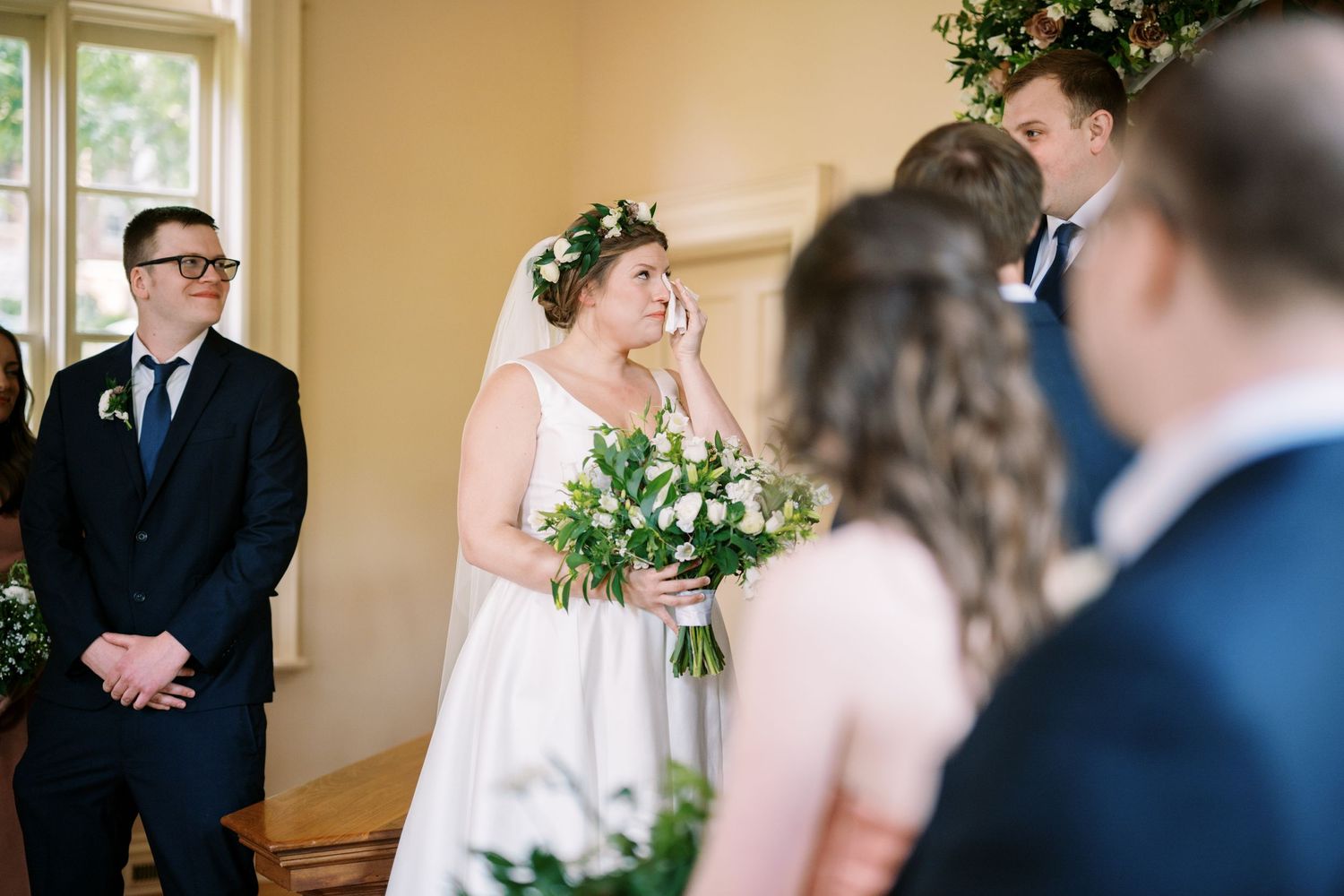 Wedding ceremony in a bright room with traditional decor and floral arrangements.