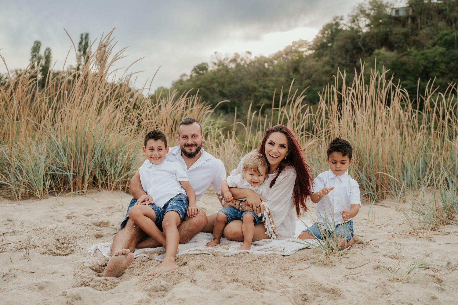 Happy family playing and laughing together on sandy beach at sunset.