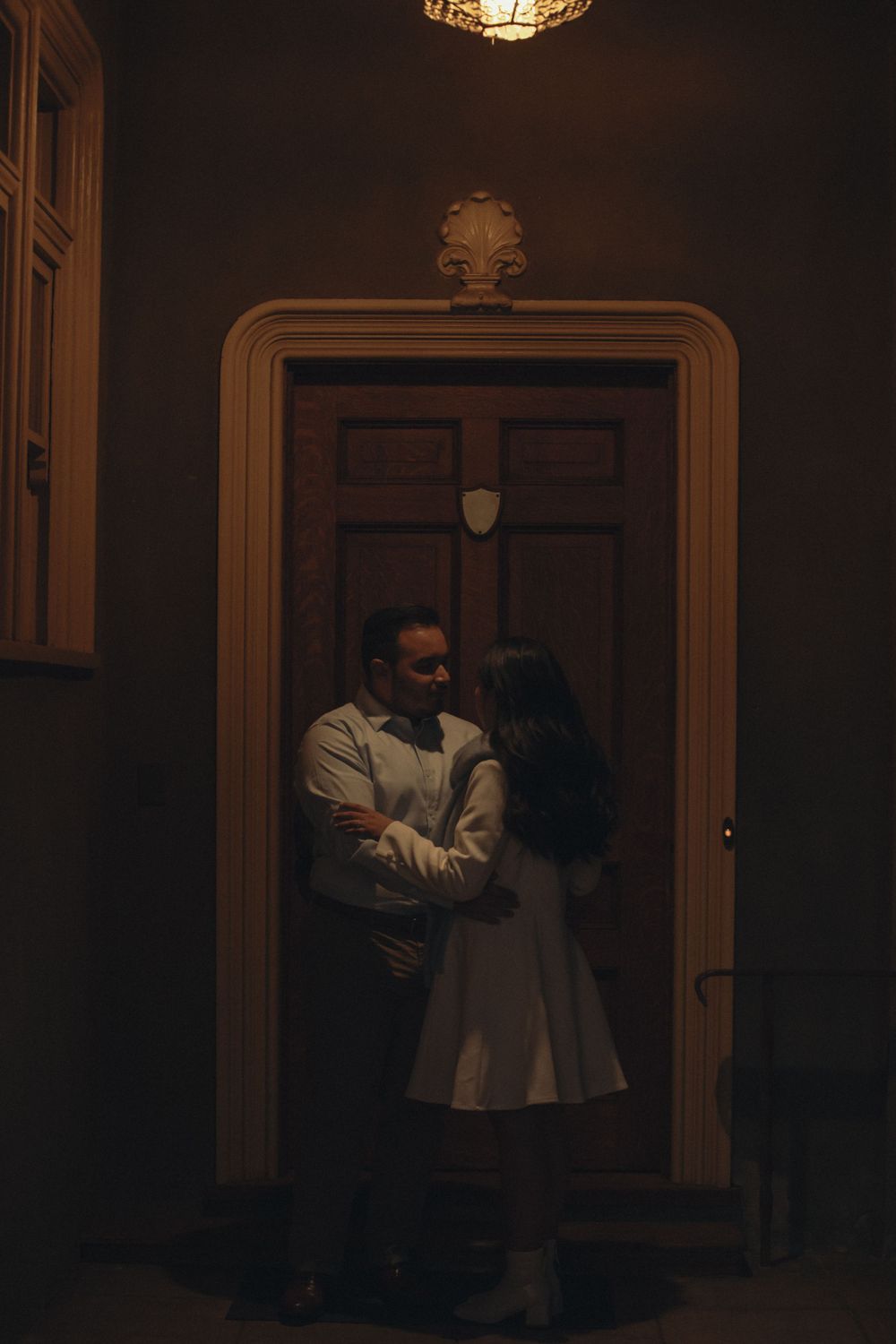 Photography of a couple dancing romantically under a chandelier at a Victorian house in Southern California for their engagement photos