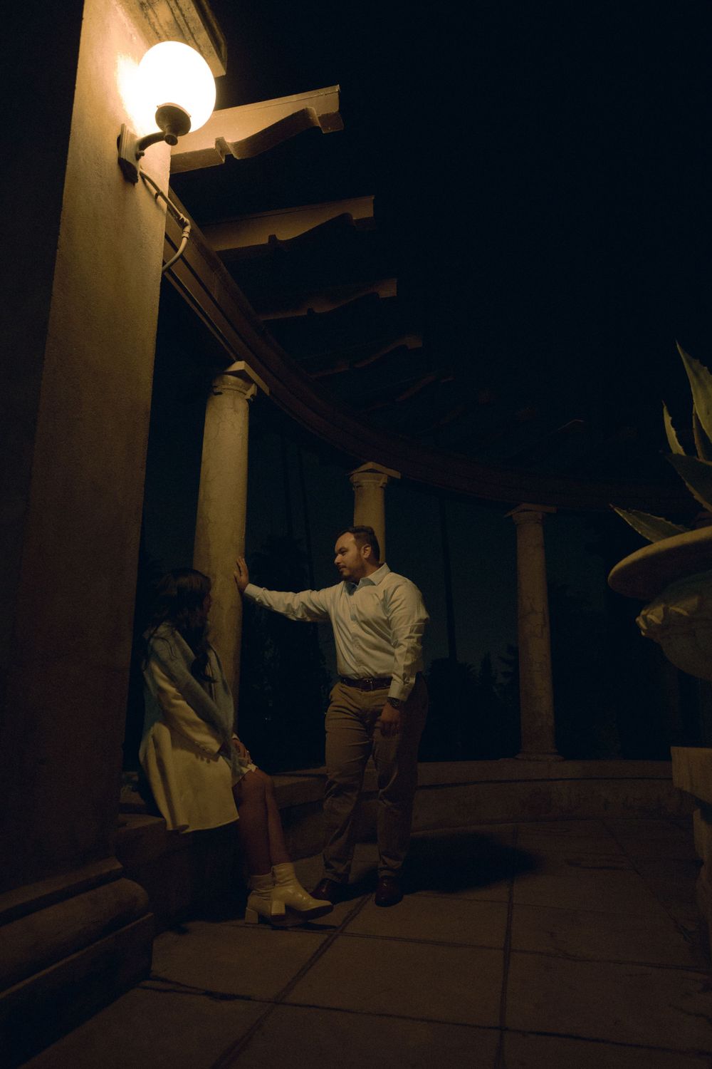 Romantic couple with illuminated columns and warm lighting creating a moody ambiance.