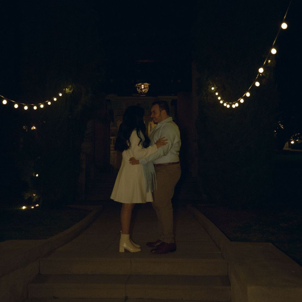A couple dances at night under string lights on outdoor steps in a romantic evening setting in Redlands, California