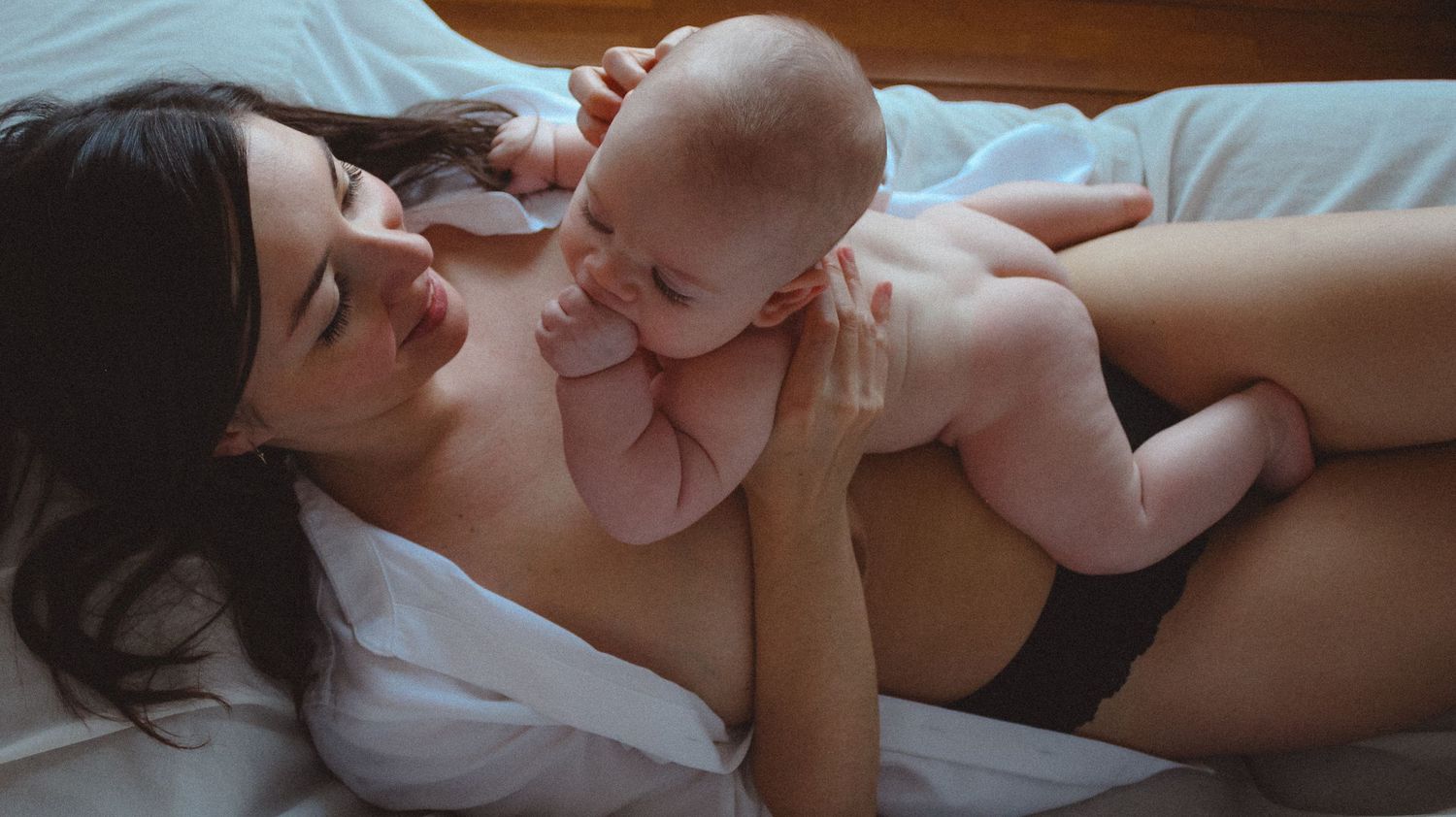 six months old baby doing skin to skin with mom on couch