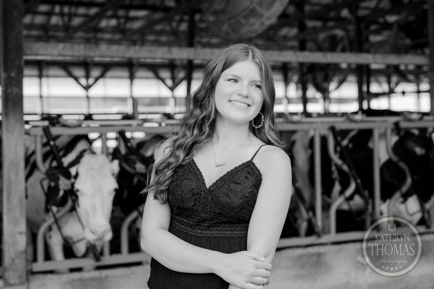 Black and white portrait showing a smile inside a dairy barn setting.