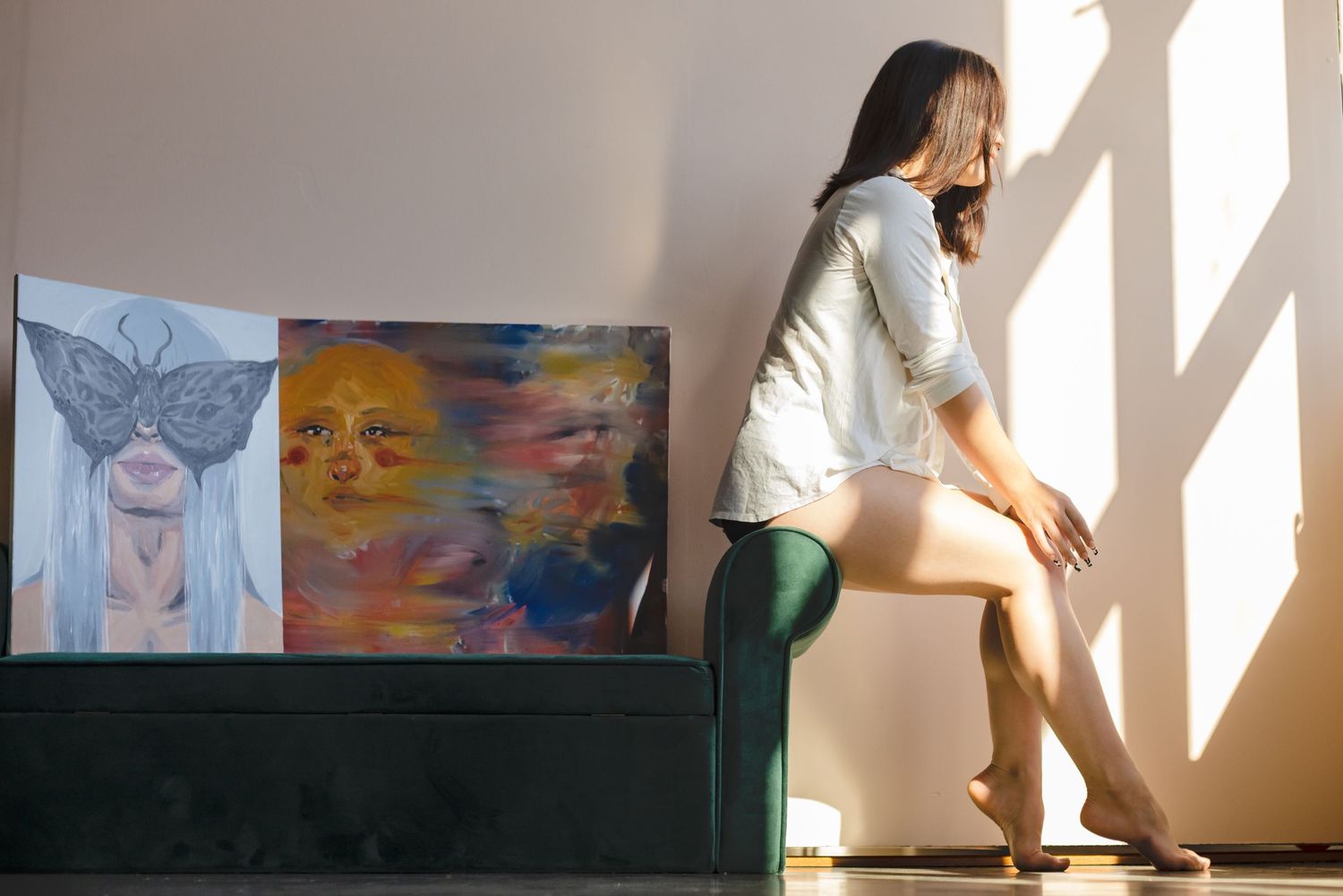 Artwork displays on dark surface near window as sunlight casts dramatic shadows on white wall.