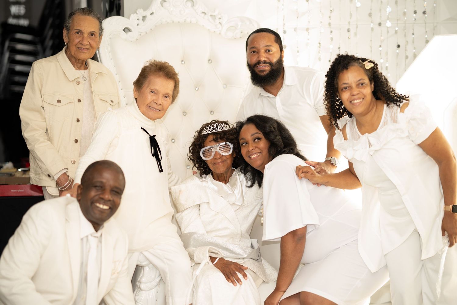 Group photo of wedding party members dressed in crisp white outfits against light background.