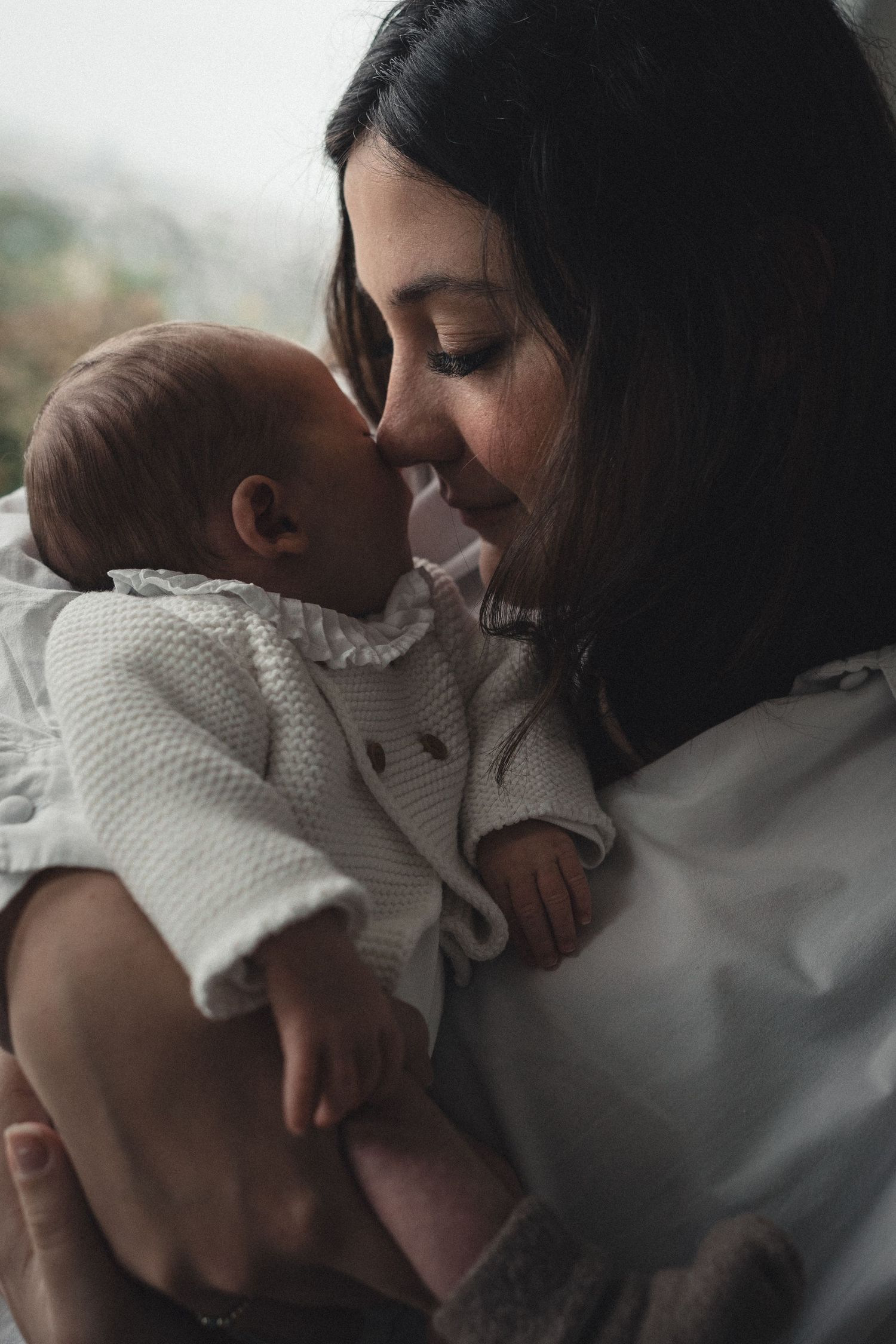 An intimate bonding moment between parent and infant swaddled in white.