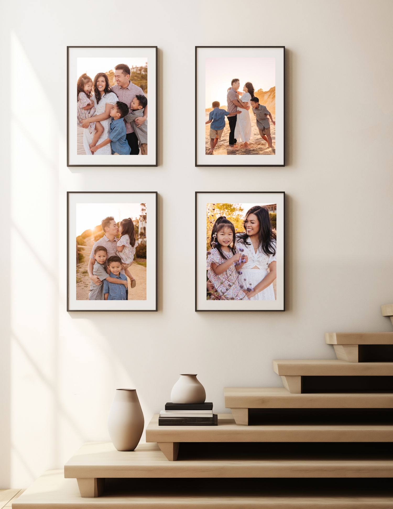 Gallery wall display of four framed photographs arranged on a white wall above modern wooden stairs with a decorative vase.