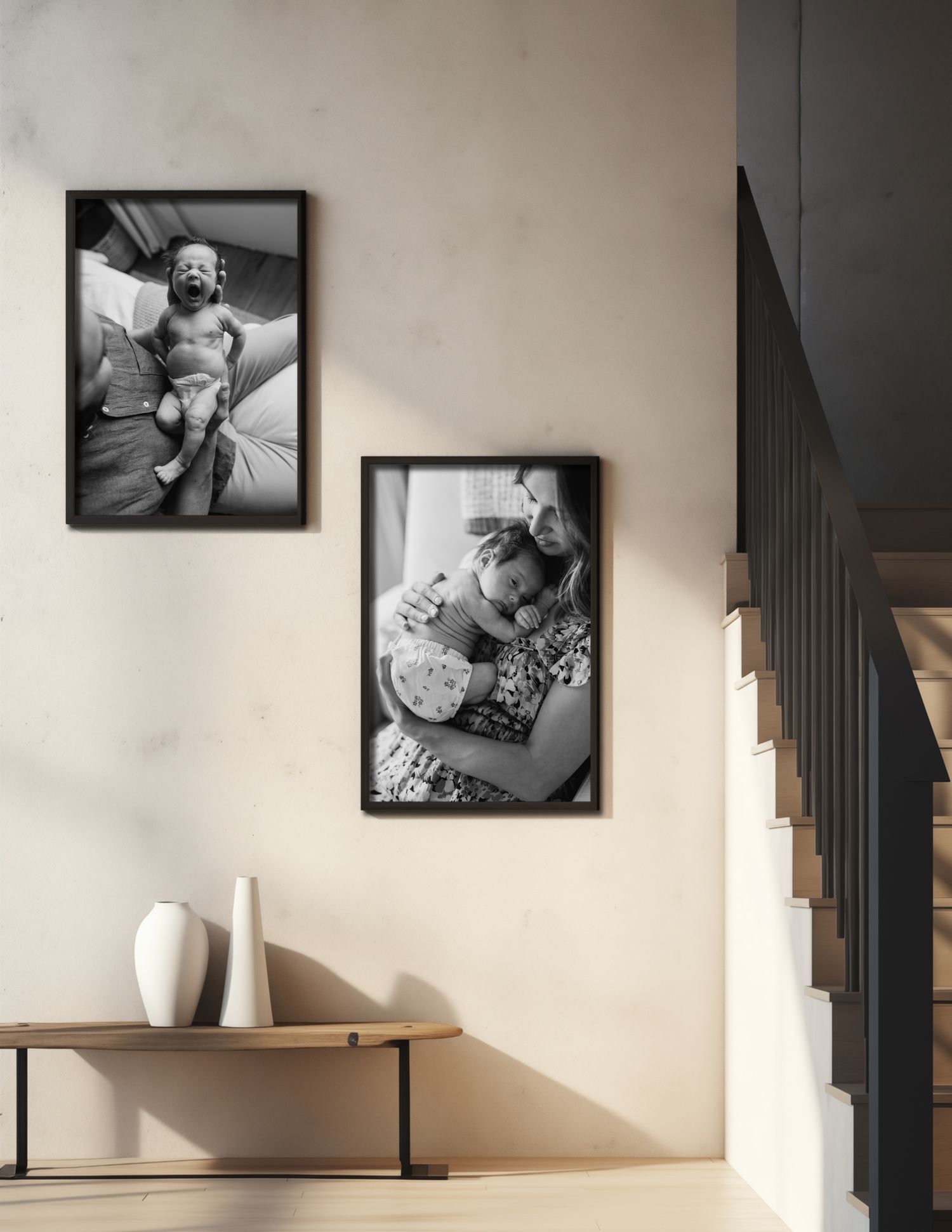 Two black and white photographs in dark frames hang on a beige wall above a wooden table with decorative vases.