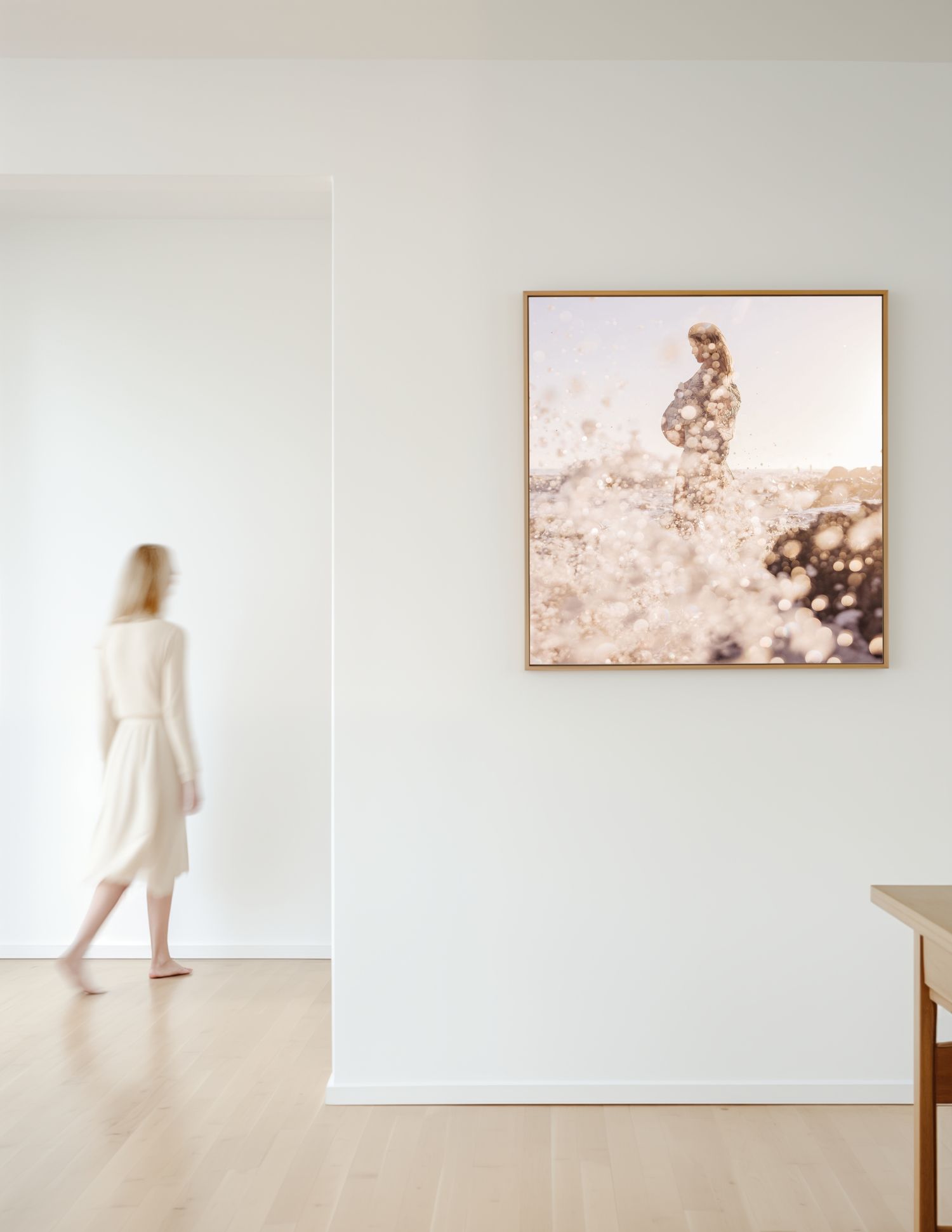 A person in white looks at a sepia-toned framed photograph on a minimalist gallery wall with hardwood floors.