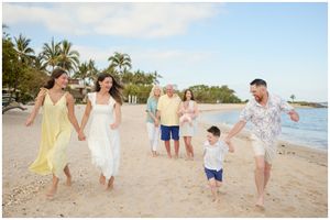 Cheerful group walking together on tropical beach with palm trees and ocean view during sunset.