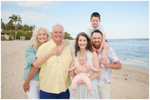 Multi-generational family gathering poses for portraits on a sunny Hawaiian beach.
