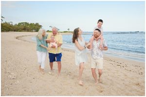 Casual family photo session with candid interactions on a scenic beach with blue waters.