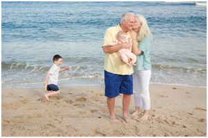 A family enjoys a sunny day together on a beach with blue ocean waves in the background.