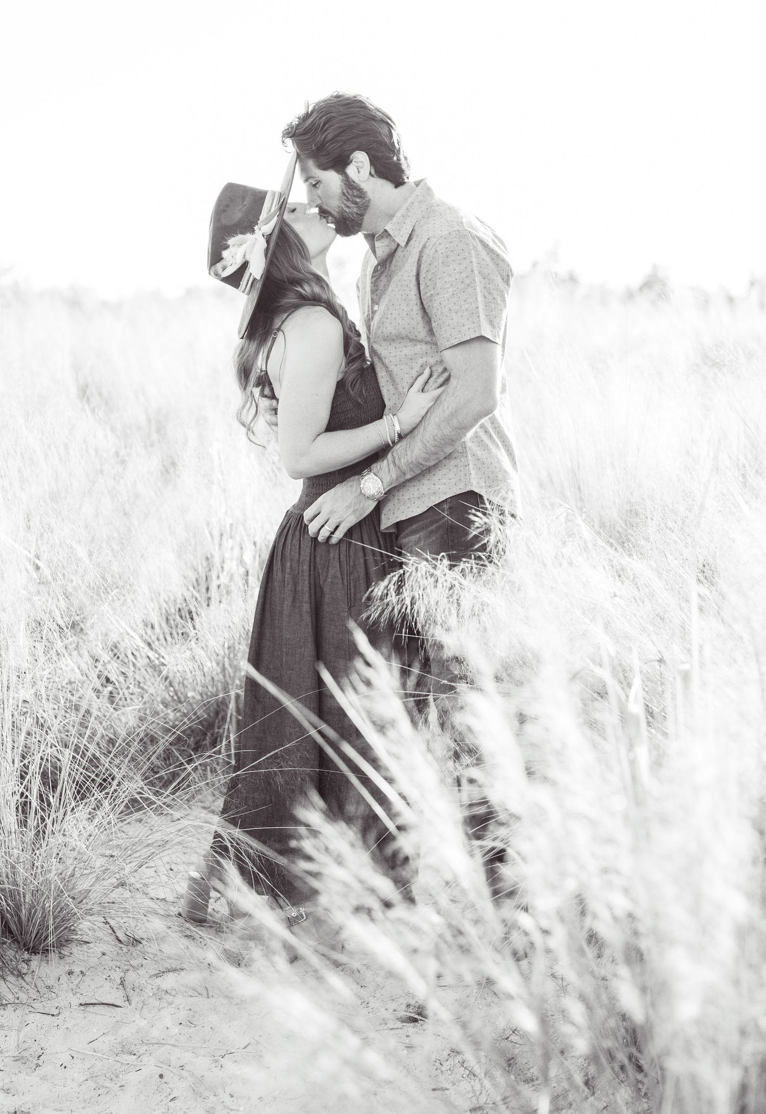 A romantic couple dancing and laughing together in a bright living room with decorative dried flowers and a candle.