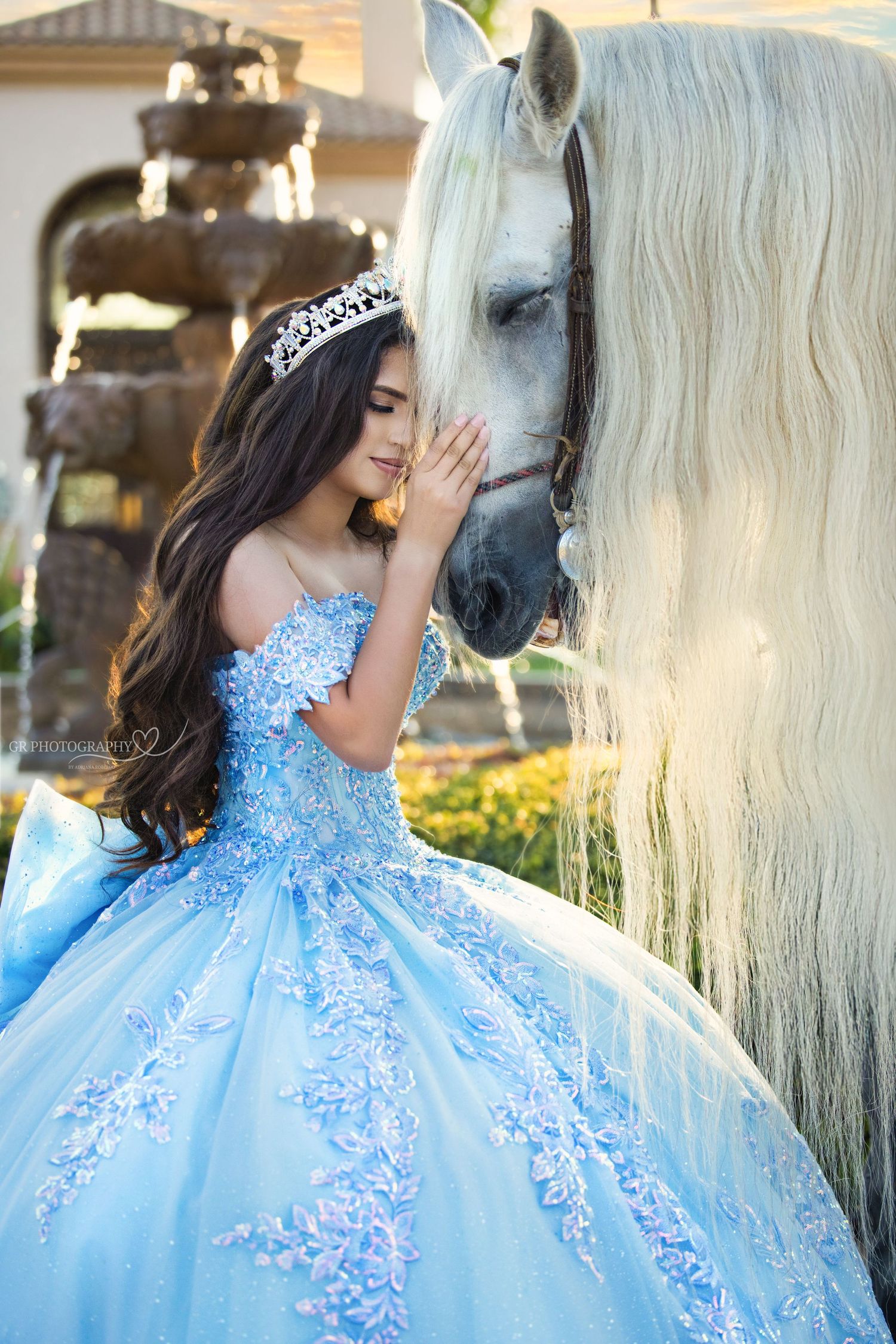 Dramatic evening portrait of a sage green ball gown with off-shoulder design amid floral arrangements.