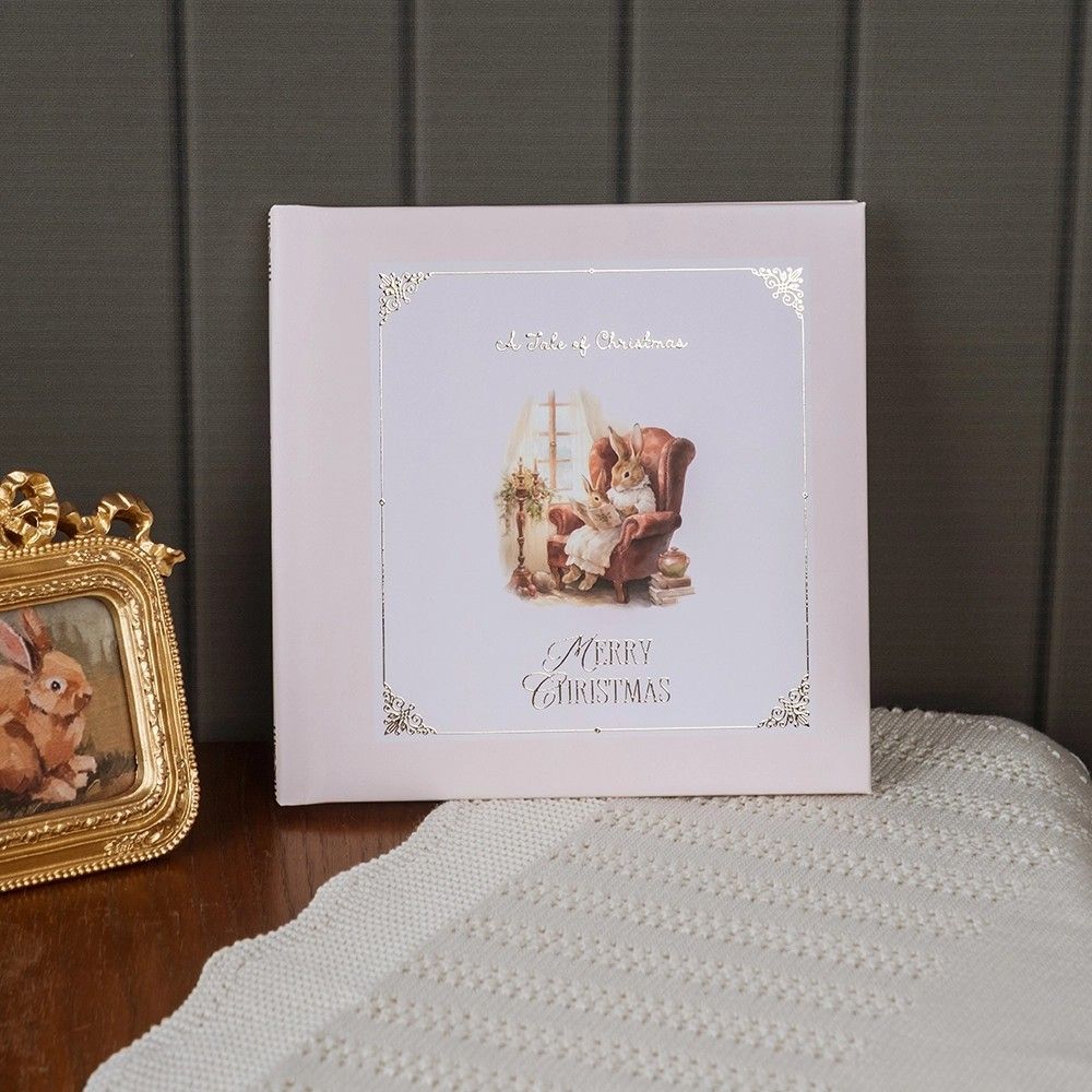 Decorative Christmas cards displayed on a white surface against a dark wall with a gold ornate frame accent.