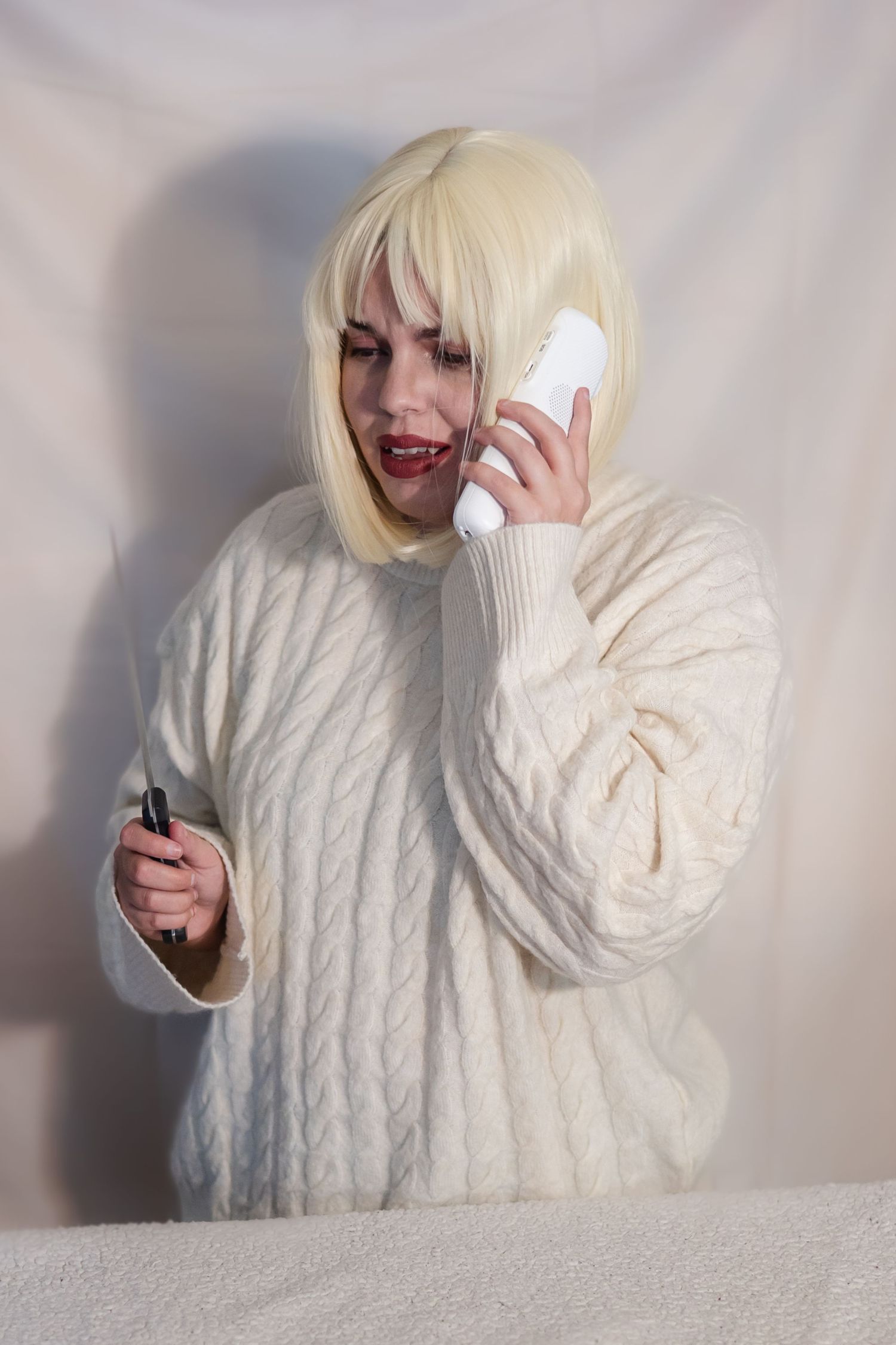 Person in white cable knit sweater posing against white wall in four sequential photos.