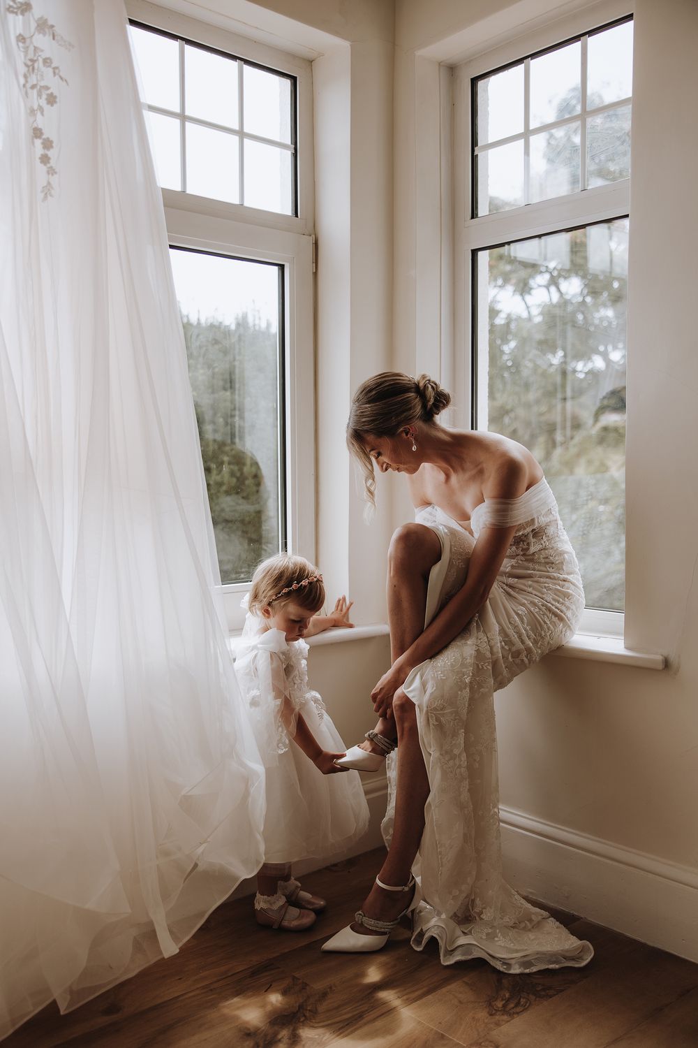 A series of intimate photos showing someone adjusting a wedding dress near bright windows with flowing curtains.