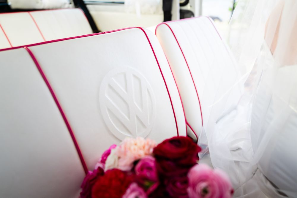 White pillow with red piping trim and decorative red and pink roses against a light background.