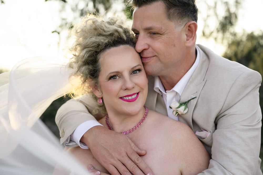 Romantic outdoor portrait of a couple in formal attire embracing during a wedding celebration.