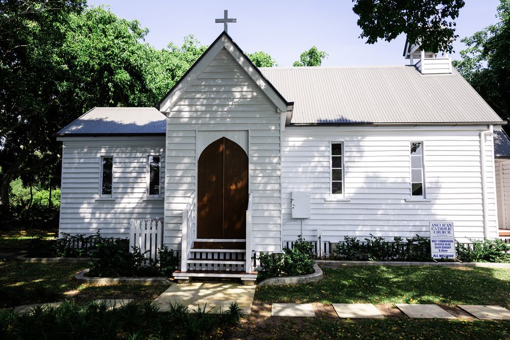 A series of white wooden church buildings with crosses and steeples nestled among trees and greenery.