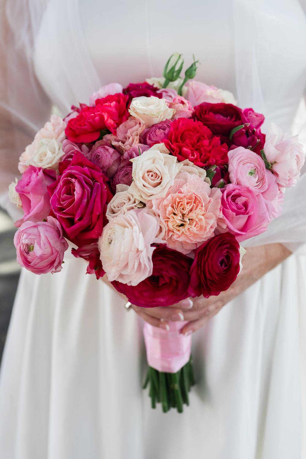 Beautiful bridal bouquet featuring pink and red roses with blush accents against a white background.