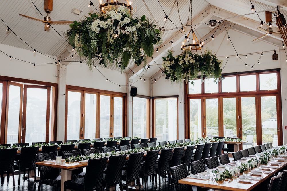 An elegant wedding reception venue decorated with hanging greenery and string lights.