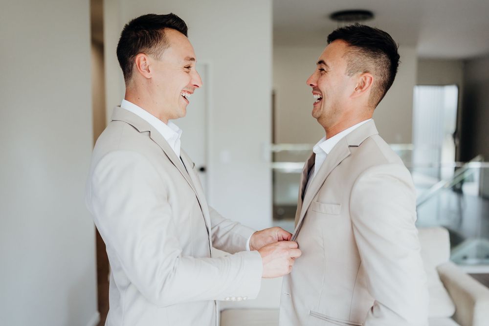 Two people in matching white outfits share a joyful moment before the ceremony.
