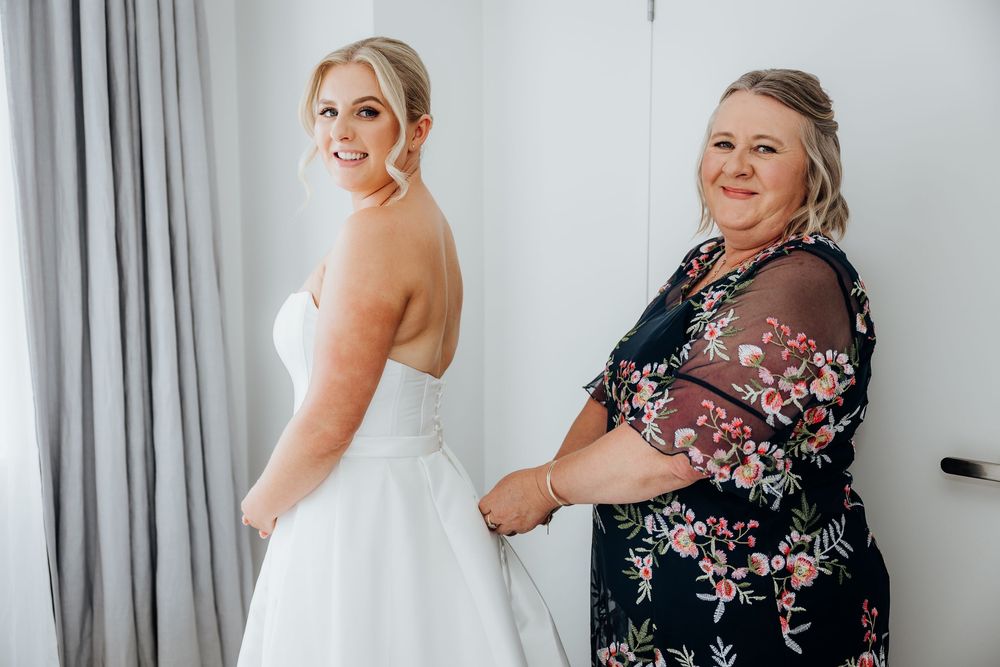 Getting ready moments captured in a bright room with floral bridesmaid dresses.
