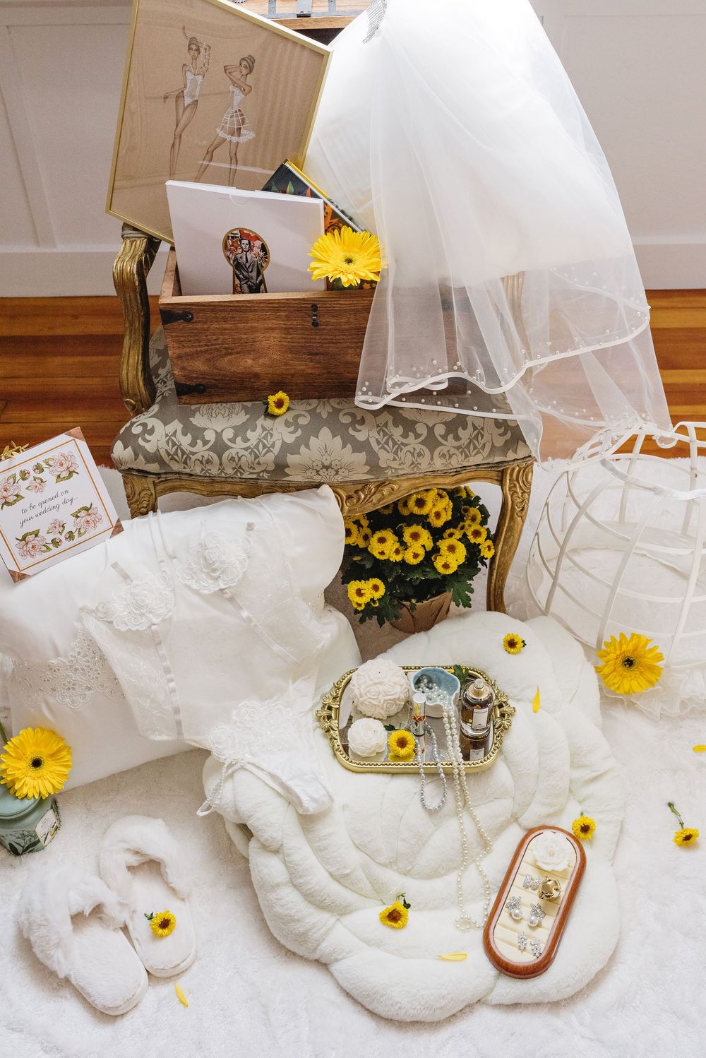 Wedding accessories display with white veil, sunflowers, and vintage decor items arranged on wooden floor.