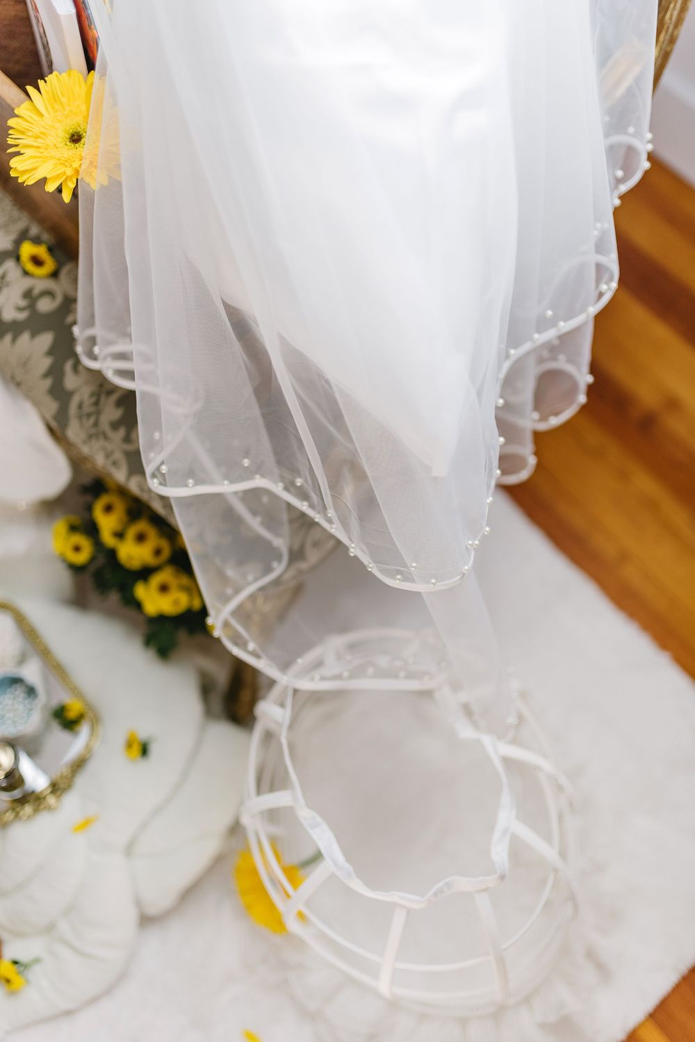 Close-up of delicate white wedding veil with scalloped edges draped over a crinoline hoop.
