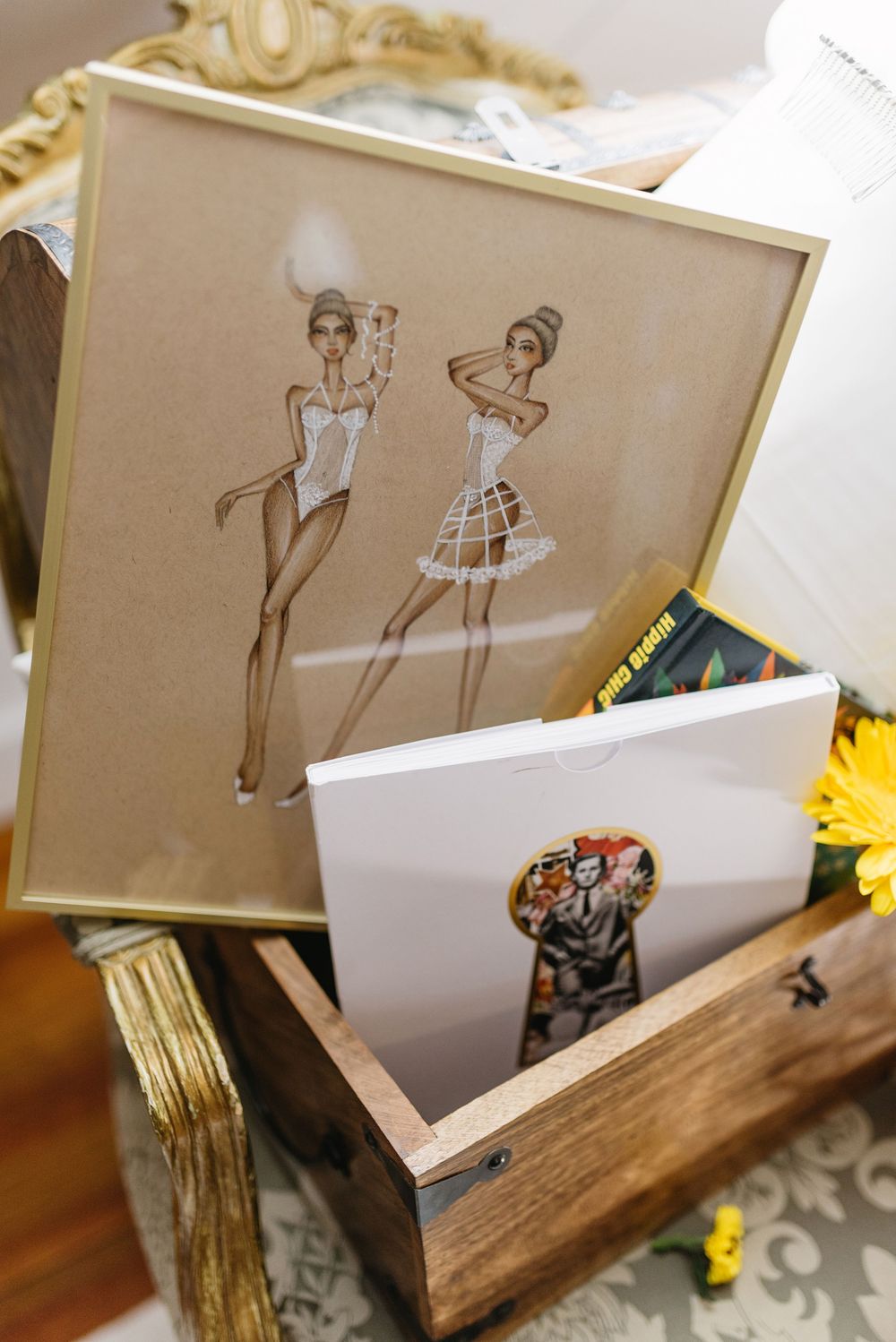 Rustic wooden display holder with framed artwork and yellow flowers.