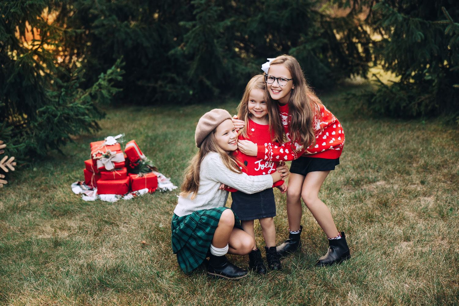 Three kids in Christmas sweaters with pine trees and presents in the background, hugging and laughing . Algonquin IL
